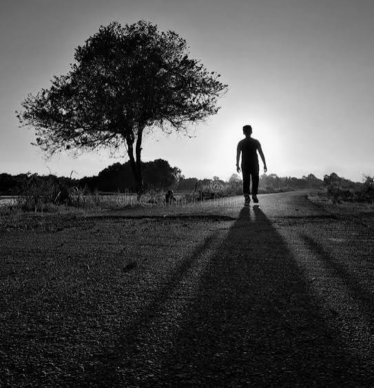 Solitary man walking on rural path at sunset in Ghana, peaceful landscape with trees and open sky.